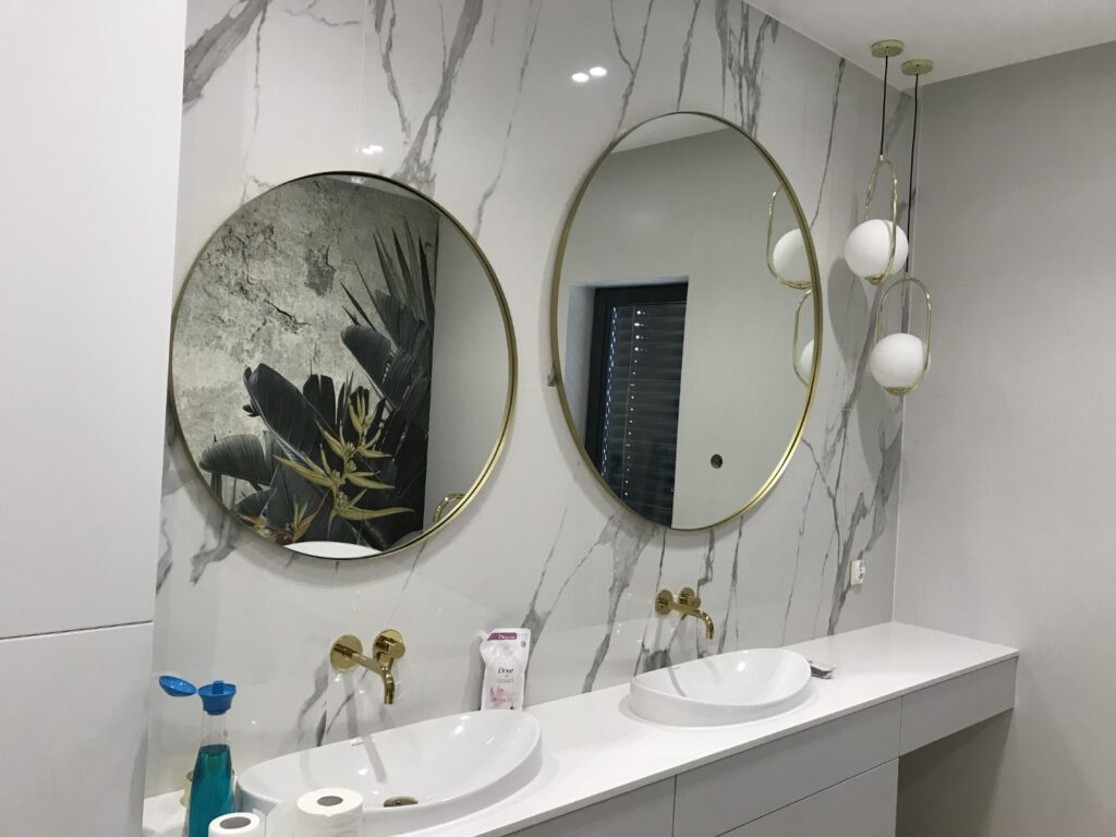 łazienka umywalki złote dodatki lustro okrągłe