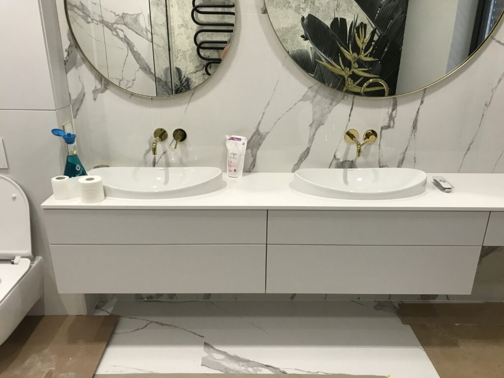 łazienka umywalki złote dodatki lustro okrągłe